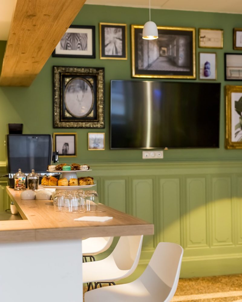 Salon vert dressé pour une pause gourmande avec écran et mange-debout — Maison Lassagne, Lyon